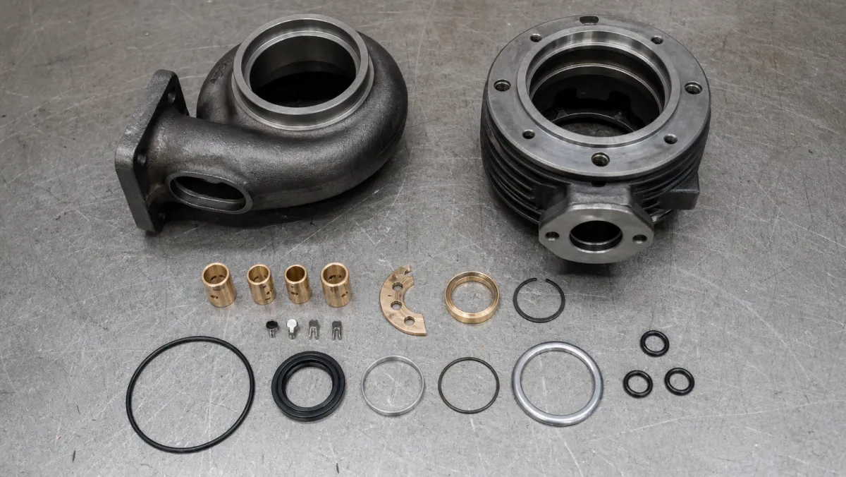 New bearings, seal rings and hardware laid out next to cleaned turbocharger housings ready for reassembly