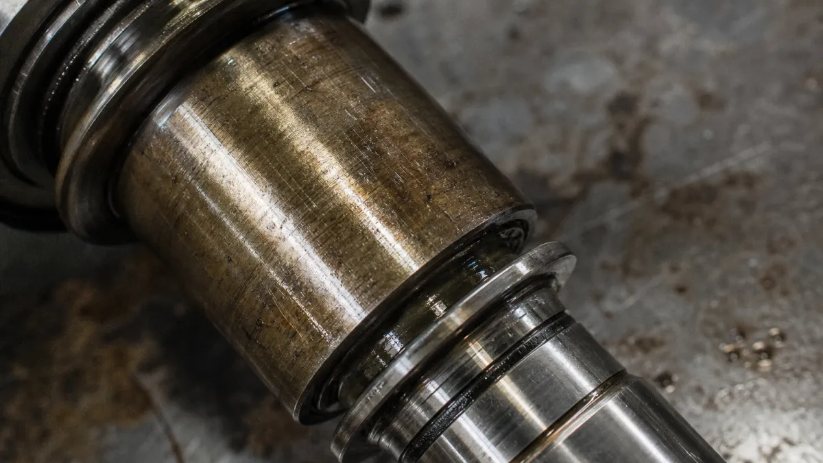 Close-up of a worn turbocharger shaft and journal bearing with visible scoring from a failed Cat C15 turbo